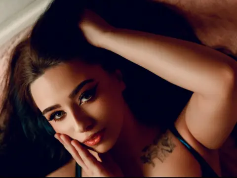 Glamorous woman with dramatic eye makeup lying down in a moody, intimate setting.
