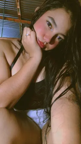 Young woman in a black tank top relaxing in warm sunlight with a dreamy, serene mood.