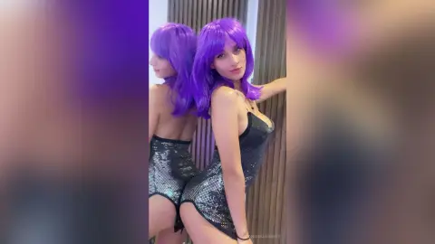 AngieSummers — Woman with long purple hair wearing a sparkly silver sequin mini dress in a modern indoor setting.