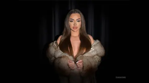 Glamorous woman in a luxurious faux fur coat posing against a dark backdrop with a moody, elegant aesthetic.