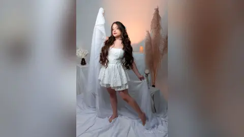 Dreamy portrait of a woman in a white lace mini dress posing in a soft, ethereal studio setting.