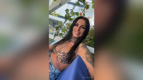 Smiling woman in a leopard print bikini top relaxing outdoors on a swing chair.