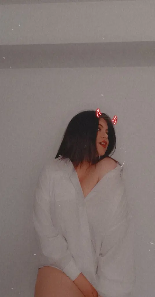 Allysoon wears a black lace bra and pink heart makeup while looking away from the camera.