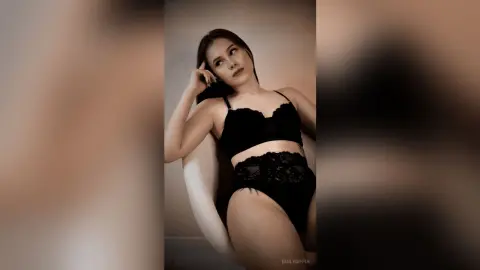 EmilyGiffin poses in black lace lingerie, wearing a bra and panties while leaning back against a white chair.