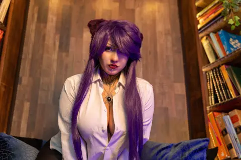 Cosplayer with long purple hair in a white button-down shirt posing in a cozy library setting.