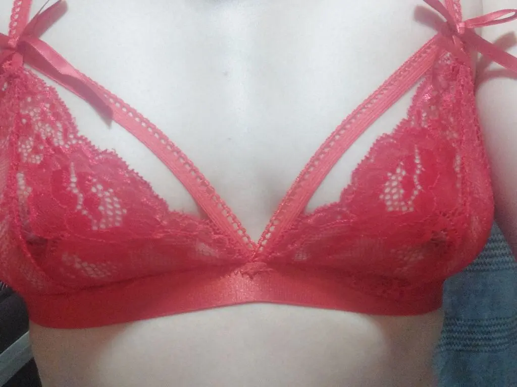Close-up of a woman wearing a romantic red lace bralette in a soft, intimate indoor setting.