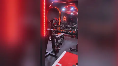 Modern dark gym interior with red neon lighting and professional weightlifting equipment for intense workouts.