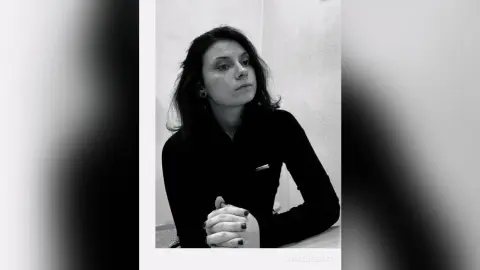 Moody black and white portrait of a woman in a dark turtleneck sweater looking thoughtfully away.