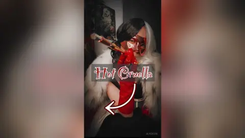 Woman in a Cruella de Vil cosplay featuring a split black and white wig, red gloves, and a white faux fur coat.