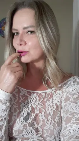 Blonde woman in a white lace long-sleeve top posing with a soft, natural expression indoors.