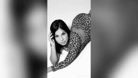 Elegant woman in a leopard print dress posing against a white background in a moody black and white portrait.