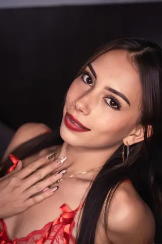 Smiling woman in a red lace outfit posing with a glamorous and romantic mood.
