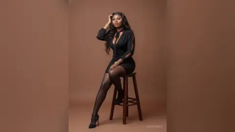 Elegant Black Woman in a Chic Black Long-Sleeve Dress Sitting on a Stool Against a Minimalist Brown Studio Background