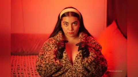 Young woman in a leopard print faux fur coat posing in warm red lighting for a cozy, moody aesthetic.