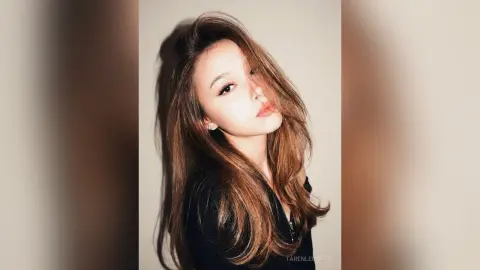 TarenLeonetti poses with long, wavy brown hair and a direct gaze, wearing a black top against a plain background.