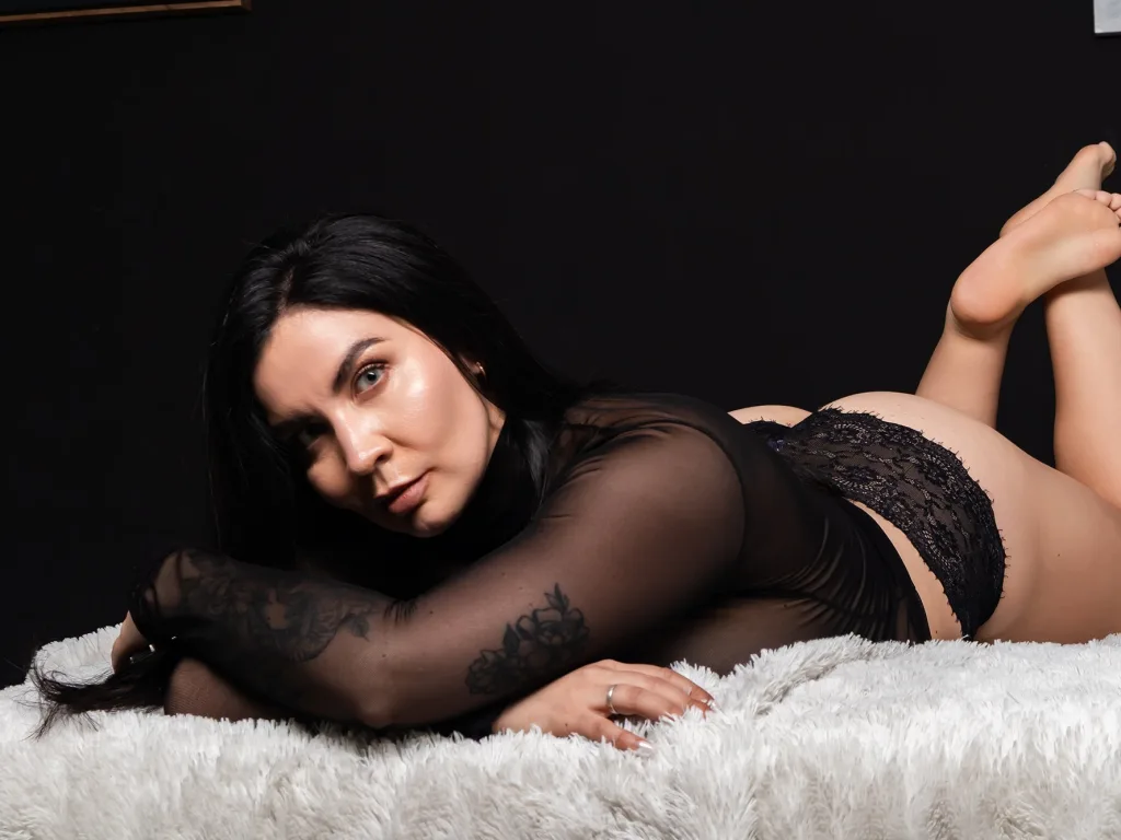 RebecaPierce poses against a red background wearing a black choker and a dark tiara in her hair.