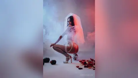 Ethereal woman in white lace lingerie and veil posing amidst dreamy pink and blue smoke clouds.