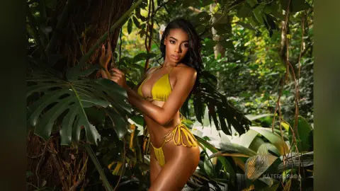 Beautiful woman in a yellow bikini posing in a lush tropical jungle setting with a serene mood.