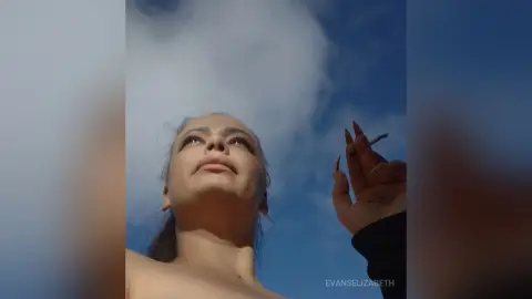 Low angle view of a woman looking up at the blue sky and clouds with a contemplative mood.