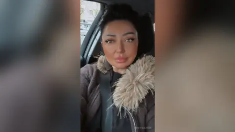 Beautiful woman in a cozy winter coat with a faux fur collar sitting in a car on a bright day.