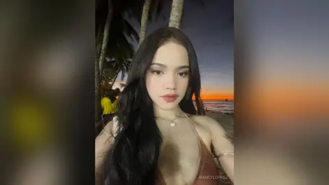 Young woman in a brown bikini relaxing on a tropical beach during a golden sunset.
