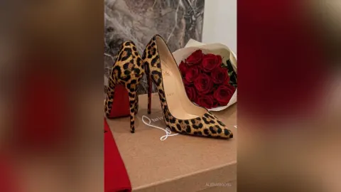 AlienaMoore — AlienaMoore leopard print high heel pumps sit next to a bouquet of red roses on a box.