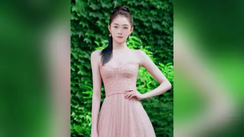Elegant woman in a sparkling pink strapless gown posing gracefully against a lush green garden background.
