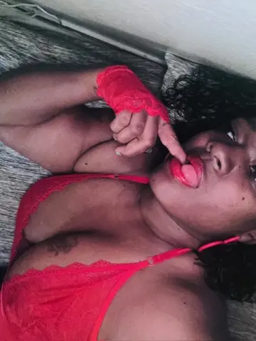 VeraMonae — Curvy woman in red lace lingerie and matching gloves relaxing on a bed with a playful mood.