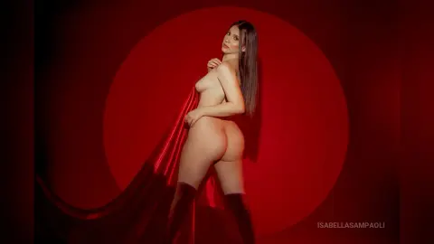 Nude woman posing against a dramatic red circular backdrop in a moody, artistic studio setting.