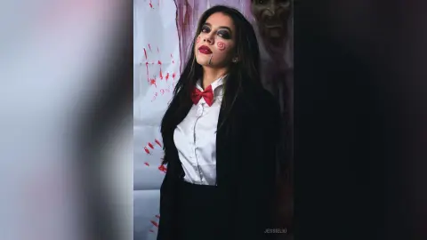 JessieLiu wears a white shirt with a red bow tie and a black blazer, featuring spiral face paint and dark red lipstick.