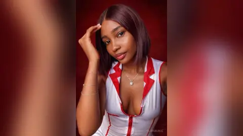 Young woman in a white and red sleeveless top posing with a confident expression against a red background.