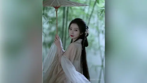 Elegant woman in traditional white Hanfu holding a paper parasol in a serene bamboo forest setting.
