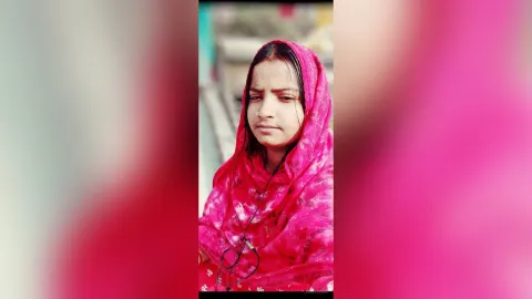 JussyAsma — JussyAsma wears a pink patterned headscarf that drapes over her shoulders and hair.
