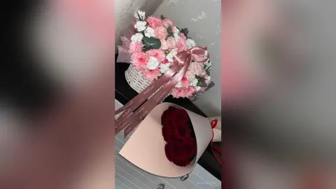 Elegant bouquet of pink and white roses in a basket next to a large bouquet of deep red roses.