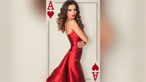Elegant woman in a red satin evening gown posing inside a giant Ace of Hearts playing card for a glamorous look.