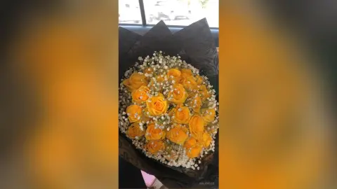 Beautiful bouquet of bright yellow roses and white baby's breath in dark decorative wrapping paper.