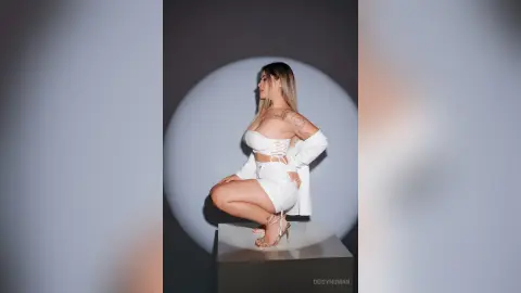 Stylish woman in a white corset outfit posing confidently in a minimalist studio setting.