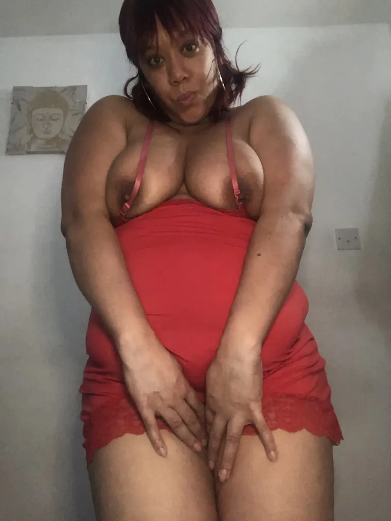 MissNaughtyCaramel has red hair and looks directly at the camera while holding a finger to her mouth in a close-up shot.