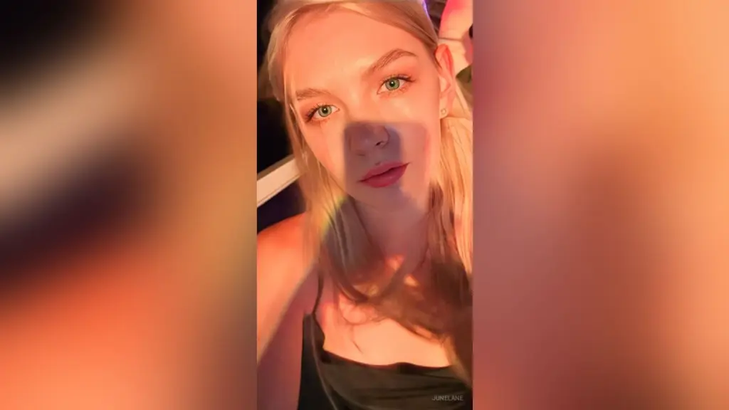 Blonde woman in a blue tie-dye crop top taking a mirror selfie in bright natural light.