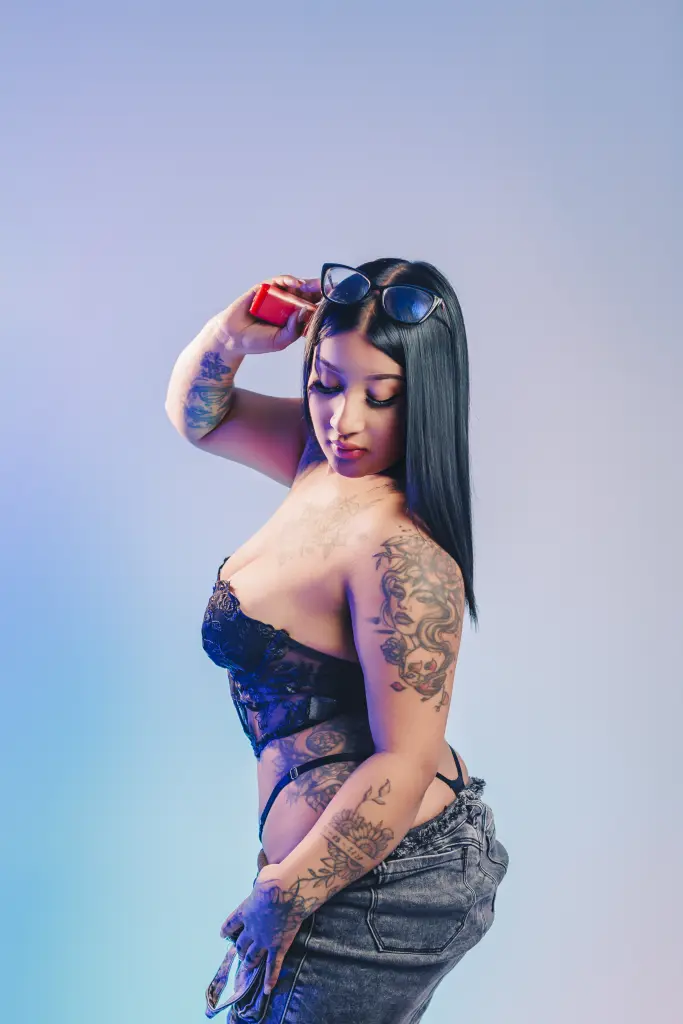 aayshel poses with her long, straight black hair hanging down her back while wearing a grey long-sleeved shirt against a plain light background.