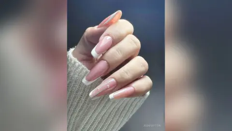 Elegant nude French tip manicure with glitter accents on long almond-shaped nails.
