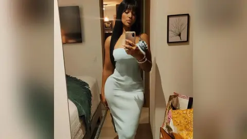 NohomiCambel poses for a mirror selfie wearing a tight, light blue sleeveless dress.