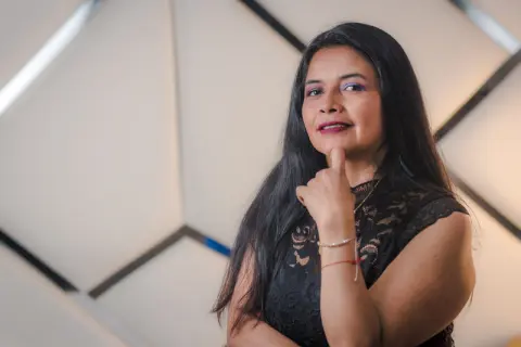 Smiling woman in a black lace top posing confidently against a modern geometric background.