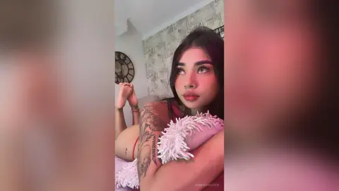 Young woman with tattoos relaxing in a cozy room wearing a white fuzzy top with a dreamy mood.