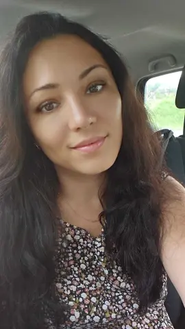FoxyKara smiling in a floral print top while sitting in a car.