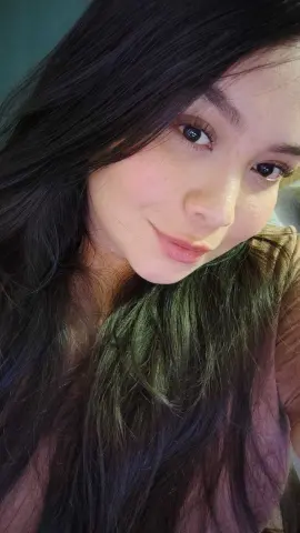 Smiling young woman with long dark hair posing for a cozy indoor portrait.
