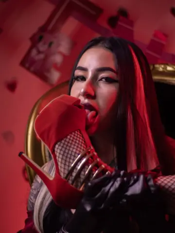 Glamorous woman in red gloves and high heels posing in moody red lighting.