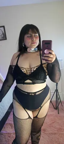 LuluPup poses in a black lace bra and high-waisted black undies with fishnet stockings and arm warmers.