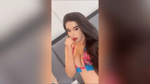 Young woman in a colorful floral bikini top posing confidently in a modern indoor setting.