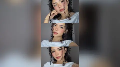 Young woman with curly hair wearing a white casual top in a soft, minimalist indoor setting.